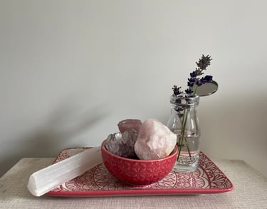 A bowl of crystals and a vase of flowers on a tray