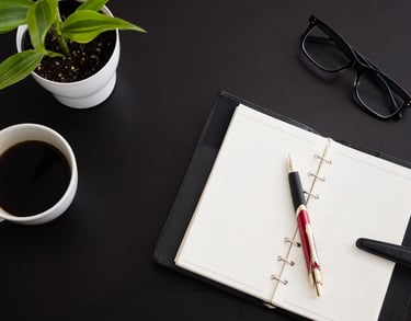 a notebook with a pen and a cup of coffee