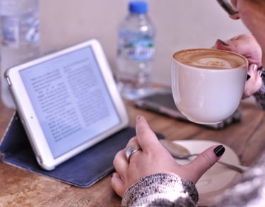 a woman holding a cup of coffee and a tablet