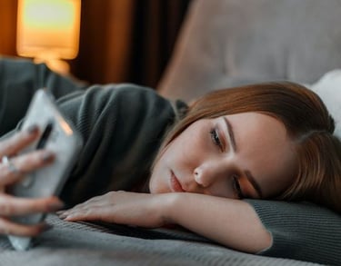 imagem de uma jovem mulher deitada no sofá vendo o celular