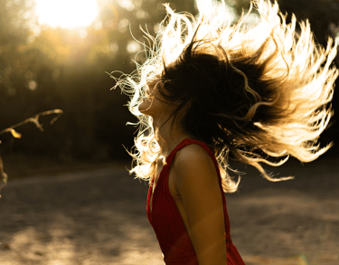 Woman in red dress tosses her long hair back dancing after acupuncture in Carbondale, CO