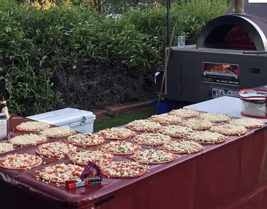 pizza-making operation with tables set up, ingredients being set up next to a pizza oven