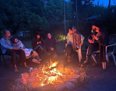 People sitting around the fire making music - photo by Birdy