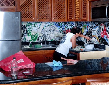 a woman designing and cleaning a mosaic  kitchen counter top