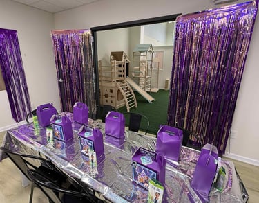 a party table with purple bags of candy and purple bags
