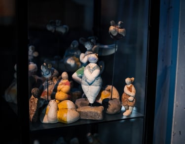 Diverse Gipsengel auf Steinsockeln in einer Glasvitrine