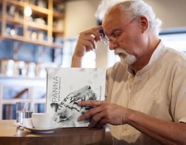 a man sitting at a table with a book and a cup of coffee