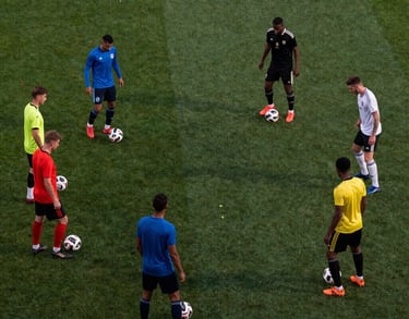 Wide shot of a soccer drill involving six players of diverse origins passing the ball in a triangular pattern. High-angle perspective, evening lighting.
