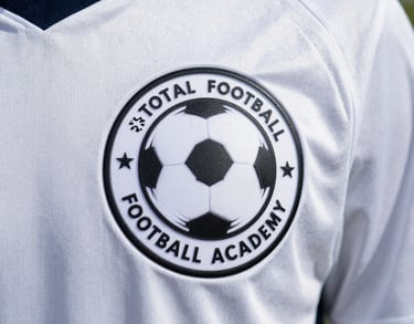 Close up of the Total Football Academy logo on a high-quality white soccer jersey worn by a young athlete.
