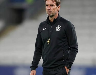 Portrait of a professional European soccer coach in his 40s, wearing a black training tracksuit with a gold whistle. Modern stadium background, soft professional lighting.