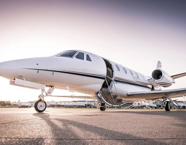Private jet parked on runway with open door.
