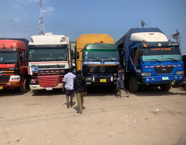 A row of colorful heavy-duty trucks—red MAN, white DAF, yellow flatbed, and blue DAEWOO—parked side 