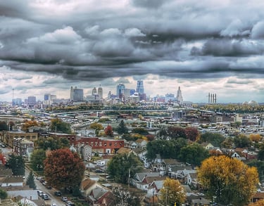 Downtown Kansas City, Missouri landscape photo taken during the fall with vibrant trees and deep, cloudy skies.