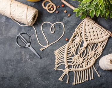 Tapiz de macramé artesanal acompañado de cordón de algodón, tijeras y cuentas de madera 