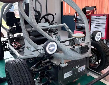 Engineers inspect a custom autonomous electric vehicle prototype with a roll cage and sensor suite.