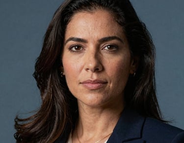 Professional headshot of a South American / Brazilian female legal expert, professional attire, soft Steel Blue background lighting.