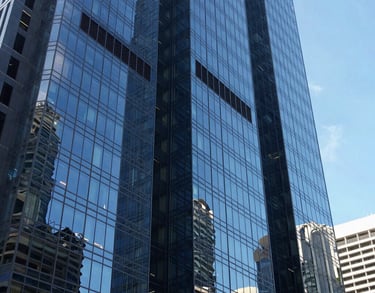 A view of a modern glass skyscraper reflecting a clear blue sky in a major Oceania / Australian city, symbolizing strength and modern legal practice.