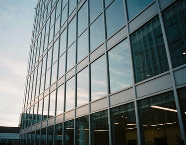 An architectural wide shot of a glass-walled conference room in a North American / US headquarters, reflecting a muted light blue sky.