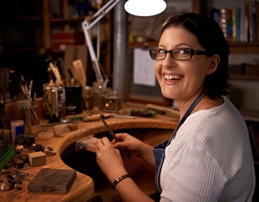 Artesana sonriente, trabajando una manualidad en un taller artesanal