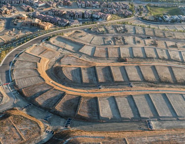 Aerial view of new housing development construction site with terraced land lots and suburban infrastructure.