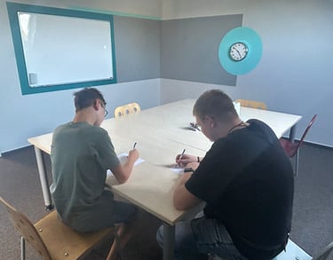 two men sitting at a table with papers and pens