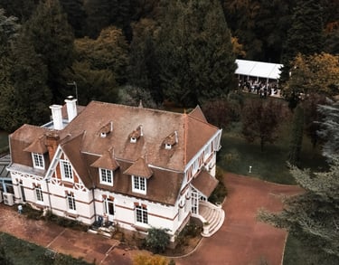Une maison normande vue du ciel dans un parc boisé