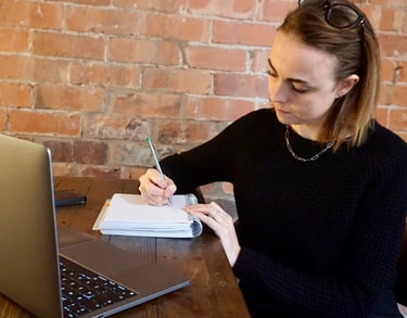Coach Moll sat in front of laptop writing in her notebook