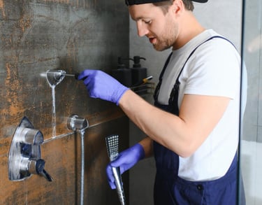 Technician wearing gloves repairing a shower tap on a tiled bathroom wall