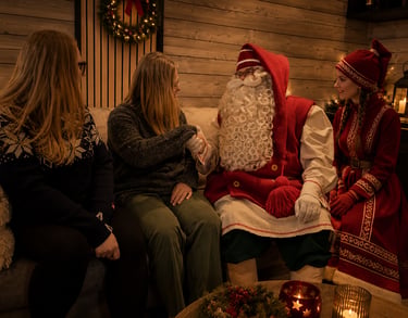 Santa Claus shares a private Christmas moment with adult guests at their holiday accommodation in Rovaniemi, Finnish Lapland.