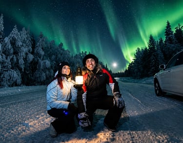 Guests viewing the Northern Lights beside a vehicle during an Aurora Hunt with Local Guide Timo in Rovaniemi