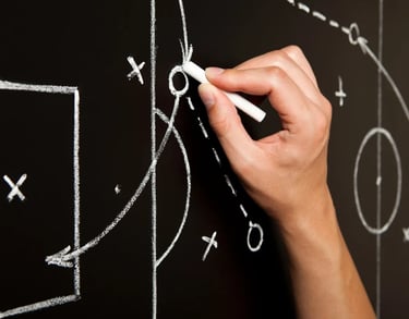 Hand diagraming a soccer play on a blackboard