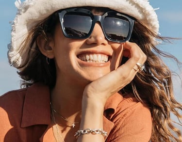 Woman smiling with designer sunglasses, available at Edge Optics