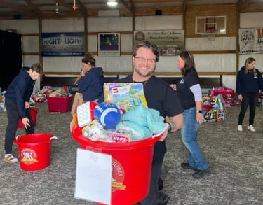 Team member from Edge Optics holding a large bin full of donated toys
