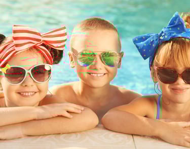 Three kids wearing protective sunglasses in a pool