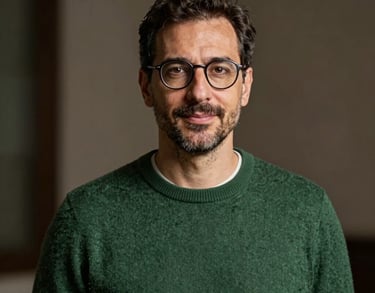 Portrait of a professional man in his 40s with glasses and a soft forest green sweater, Southern European / Italian background, elegant and approachable.