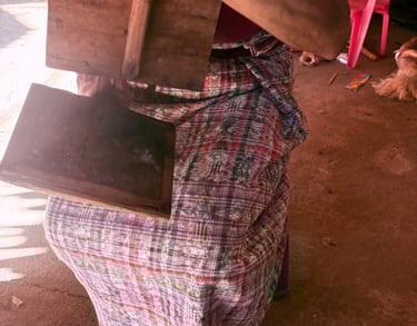 Un artesano guatemalteco, con vestimenta tradicional maya, utiliza cardas manuales de madera