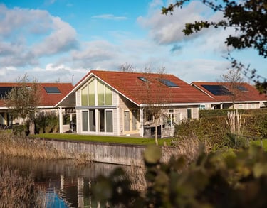  Luxuriöse Ferienhaus in einem Ferienpark direkt am Wasser mit Solaranlage und rotem Ziegeldach.