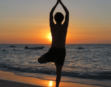 a man standing on a beach with a sunset in the background
