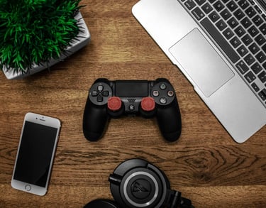 Variedad de aparatos electronicos, control ps4, laptop y celular