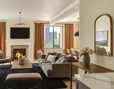 Modern luxury living room with a grey sofa, marble fireplace, and city skyline view through the window.