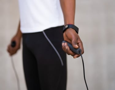 A person in fitness gear holding jump rope handles during a cardio workout session.