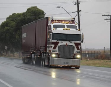 a semi truck driving down a road in the rain