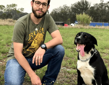 o adestrador alvaro israel agachado de lado de um cão tranquilo