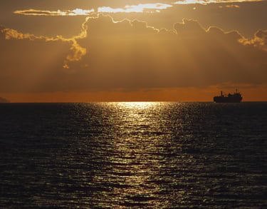 a ship sailing in the ocean at sunset