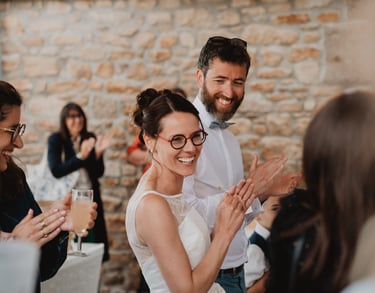 deux mariés heureux et souriant entourés de leurs invités