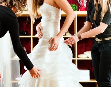 a woman in a wedding dress is helping a bride