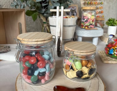Bonbons dans des bonbonnières posées sur un dessous de plat en bois, candy bar