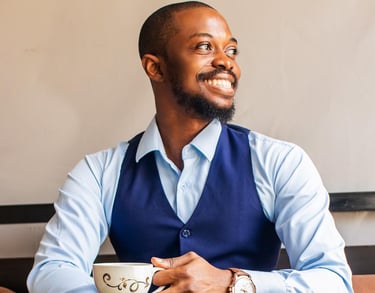 a man wearing a blue semi-formal attire holding a cup of tea