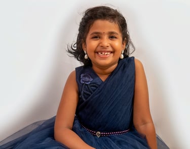 a young girl in a blue dress smiling and holding a cake