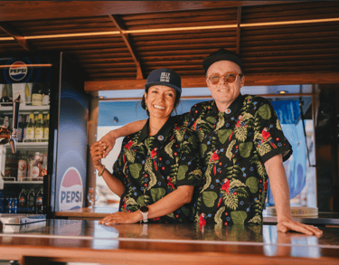 Maria og Ulrik i Maritime Munchies food truck, smiler bak disken med drikkevarer i bakgrunnen.